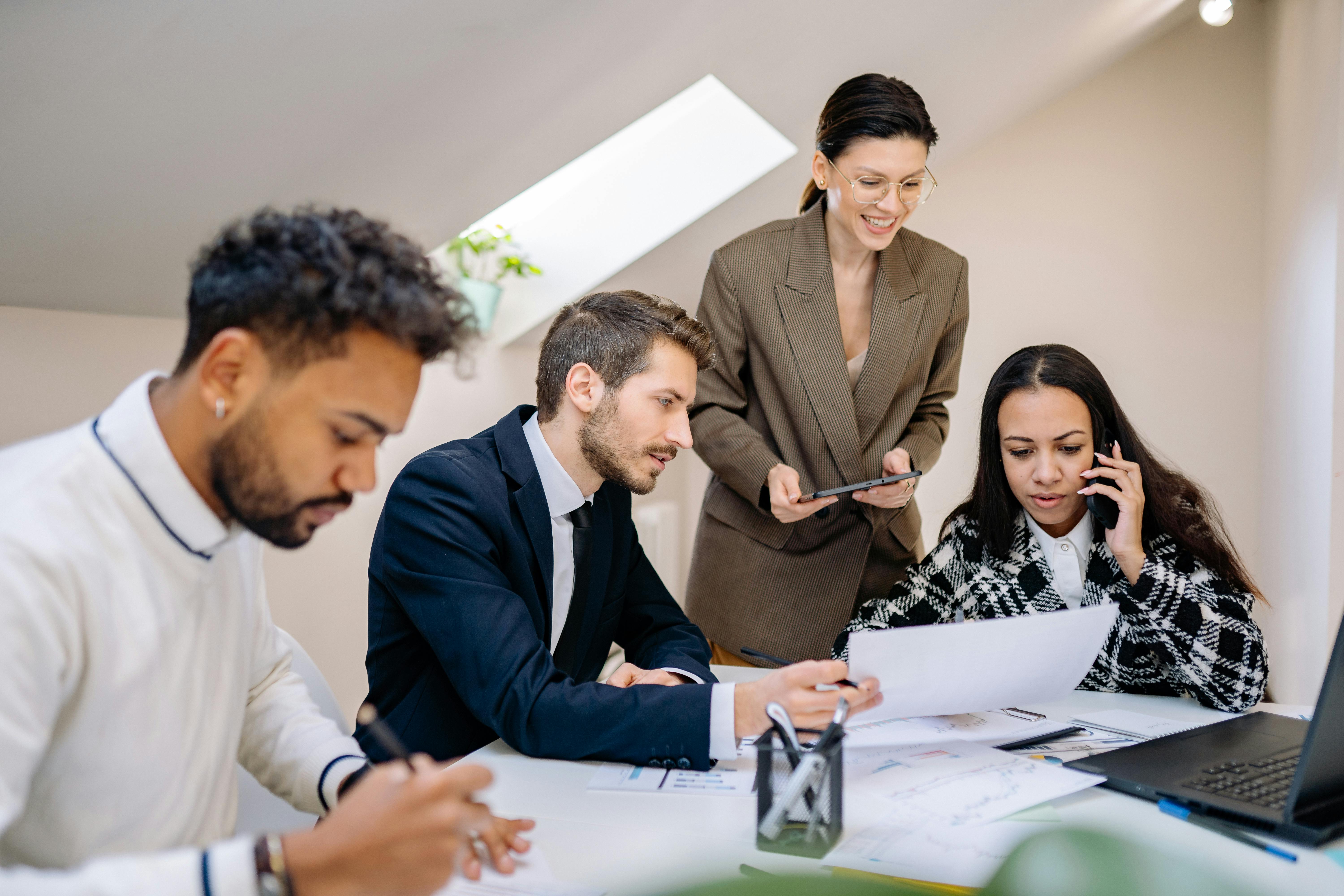 Group of professionals collaborating in a bright, modern office environment with digital devices.